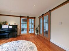 an empty living room with a piano in the corner