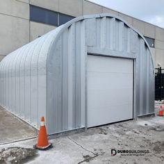 a large metal building with an orange cone next to it