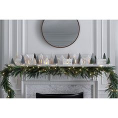 a mantel with candles and evergreen garland on it in front of a mirror over a fireplace