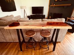 two stools sit at the end of a wooden table in front of a couch