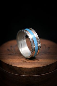 Product Details Ring Style:Acustom, handcrafted men's wedding ring featuring athin turquoise inlay and two 14K rose gold inlays. Additional inlay options are available upon request. Width:The width of the ring pictured is approximately 7-8mm wide but can be ordered in a custom width for a small upgrade cost. Please state your desired width in the Notes to Seller section during checkout, and we will reach out to you for payment. Customizable:Because each of our rings are handcrafted to order, wec Damascus Steel Wedding Band, Damascus Steel Ring, Staghead Designs, Men's Wedding Ring, Ceramic Rings, Detailed Ring, Ring Pictures, Handcrafted Rings, Unisex Ring