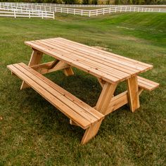 a wooden picnic table sitting on top of a lush green field