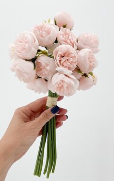 a hand holding a bouquet of pink flowers