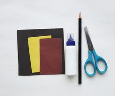 a pair of scissors, glue and some paper on a white surface with a piece of cloth next to it