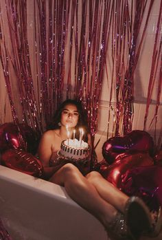 a woman sitting in a bathtub with a birthday cake