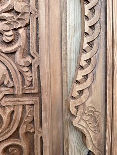 an intricate carved wooden door handle on the side of a building with wood panels and carvings