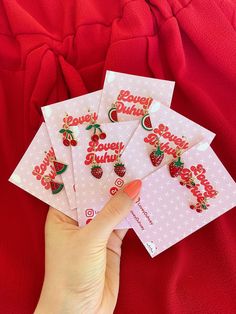 four strawberry earrings are shown in front of a red background, with the words berryy buddha written on them