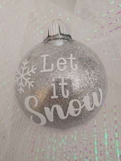 a silver ornament with the words let it snow on it's side