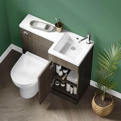 a white toilet sitting next to a bathroom sink under a mirror on top of a wooden cabinet