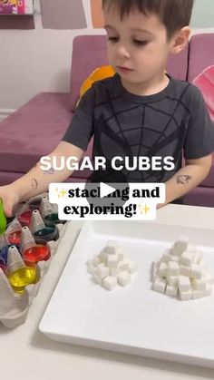 a young boy sitting at a table with sugar cubes in front of him and the words sugar cubes stack up and exploring