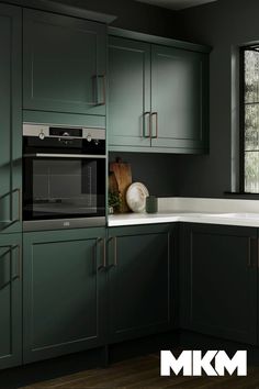 a kitchen with dark green cabinets and white counter tops, along with a window over the sink