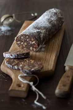 a loaf of bread sitting on top of a wooden cutting board next to knifes