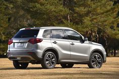 a silver suv parked in front of some trees