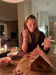 a woman sitting at a table in front of a gingerbread house with candles on it