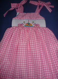 Hand smocked summer dress with pink elephants and circus. Ties at the shoulders and back. This could be a birthday dress. For other sizes allow 3 tweeks Playful Smocked Dress With Smocked Bodice For Summer, Playful Pink Dress With Smocked Back, Pink Smocked Dress For Playtime In Summer, Pink Smocked Dress For Summer Playtime, Playful Summer Smocked Dress, Playful Summer Smocked Dress With Smocked Back, Cute Pink Smocked Dress With Smocked Back, Playful Pink Dress With Smocked Bodice, Playful Pink Smocked Dress With Ruffles