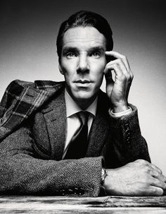 a black and white photo of a man in a suit with his hand on his head