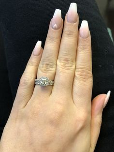 a woman's hand with a diamond ring on her left hand and white nails