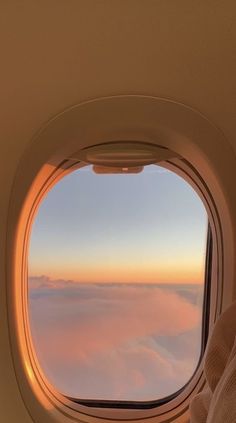 an airplane window with the view of clouds and sky from it's seat area