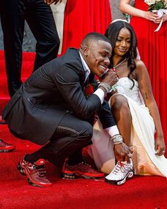 a man kneeling down next to a woman on a red carpet