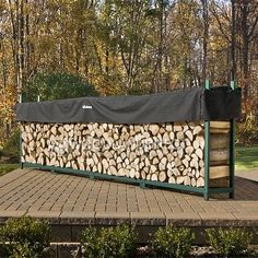 a large pile of logs sitting on top of a brick floor next to trees in the background