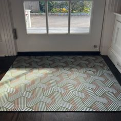 a room with a large rug on the floor next to a door and windows in it