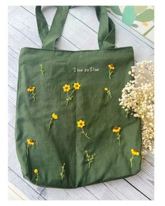 a green tote bag with yellow flowers on it