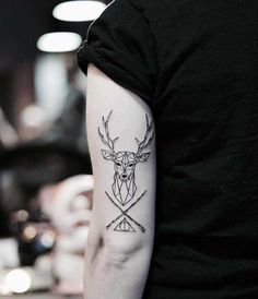 a man with a deer head and two crossed swords tattoo on his left upper arm