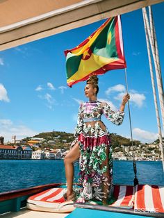 a woman holding a flag on top of a boat