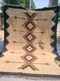 an old native american blanket is displayed on the sidewalk in front of a tree with no leaves