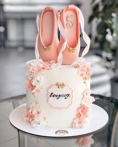 there is a white cake with pink flowers on it and two pairs of shoes on top