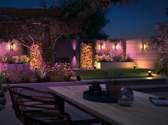 an outdoor dining area at night with lights on the walls and plants growing in pots