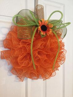 an orange tulle wreath hanging on a door with a burlock and flower