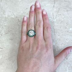 a woman's hand with a green and white ring on top of her finger