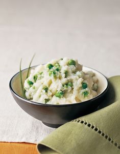 a bowl filled with mashed potatoes on top of a green napkin next to a fork