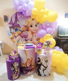 a table topped with lots of balloons and tin canisters filled with princesses