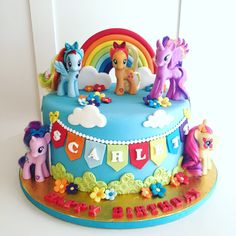 there is a cake decorated with little pony's and rainbows on the top