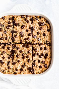 a white casserole dish filled with oatmeal and chocolate chip bars