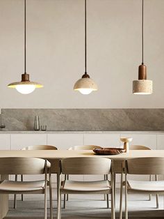 a dining room table and chairs with lights hanging from the ceiling above it in an open space