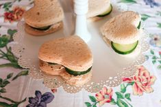 four sandwiches on a plate with cucumbers