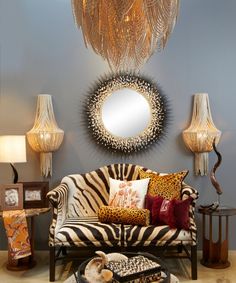 a living room with zebra print couches, lamps and mirrors on the wall above them