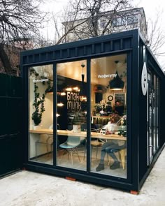 a black shipping container sitting on the side of a road next to a building with lots of windows