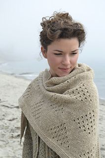 a woman wearing a shawl on the beach