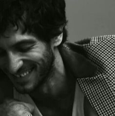 black and white photograph of a man smiling with his hand on his face while holding an apple