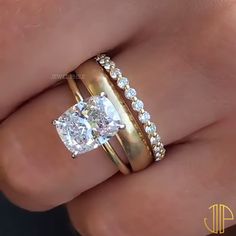 a woman's hand with two gold rings and a diamond ring on her finger