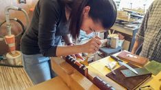 a woman is working with wood in a workshop