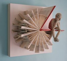 an origami sculpture made out of books is hanging on the wall next to a stuffed animal