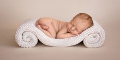 a baby sleeping on top of a blanket covered in white crocheted yarns