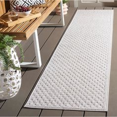 a white rug is on the floor next to a wooden bench and potted plant