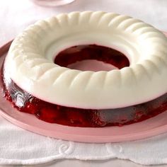 a jelly cake on a pink plate with white frosting and raspberry sauce