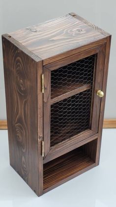 a wooden cabinet with chicken wire on the front and side doors, sitting on a white surface